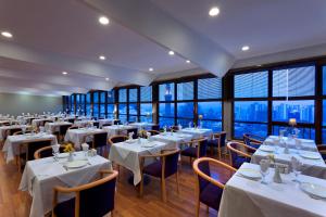 a restaurant with white tables and chairs and windows at Kent Hotel in Bursa