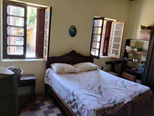 a bedroom with a bed and two windows at Hospedagem in São Gabriel