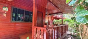 a red house with a wooden railing on a porch at Longtail Beach Resort in Thong Nai Pan Yai