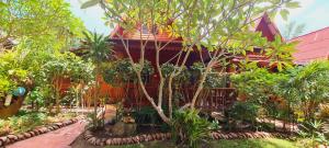 a red house with trees and plants in front of it at Longtail Beach Resort in Thong Nai Pan Yai