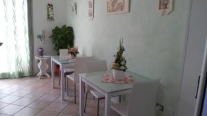 un comedor con mesas blancas y sillas blancas en B&B Le Rose, en Olbia