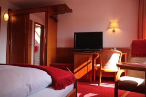 フロイデンシュタットにあるホテル ランドハウス ヴァルデスルーのベッド1台、薄型テレビが備わるホテルルームです。