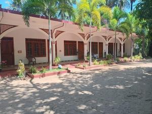 a building with palm trees in front of it at French Garden Eagle Wings Inn in Trincomalee