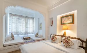 a white bedroom with two beds and a window at Kankarwa Haveli in Udaipur