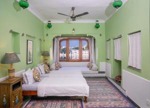 a green bedroom with two beds and a window at Kankarwa Haveli in Udaipur +27 photos