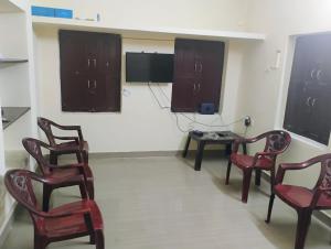 蒂鲁奇奇拉帕利Thiruveesar SVK Homestay的一间带椅子和桌子的房间以及一台电视