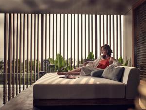 a woman sitting on a bed in a room at Regent Phu Quoc in Phú Quốc