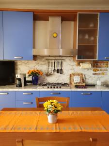 a kitchen with blue cabinets and a table with flowers at Una Terrazza su Como - Vista Panoramica in Brunate +10 photos