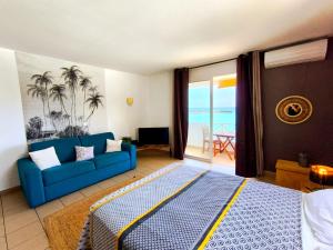 a living room with a blue couch and a view of the ocean at Le Caro - Studio pieds dans l'eau in Saint-Gilles les Bains