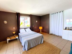 a bedroom with a bed and a large window at Le Caro - pieds dans l'eau - clim - wifi in Saint-Gilles-les-Bains