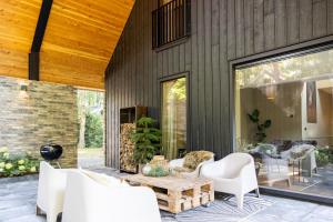 a patio with white chairs and a wooden table at midden in de bossen bij schapendrift 29 in Appelscha