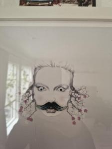 a drawing of a man with a mustache on a wall at The pink googly eyed house in Tjelta