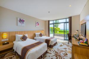 a hotel room with two beds and a television at The Reed Hotel in Ninh Binh