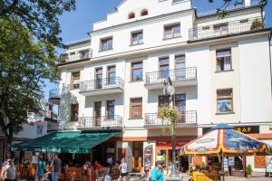 a large white building with people walking in front of it at Apartamenty Zakopane Krupówki in Zakopane +94 photos