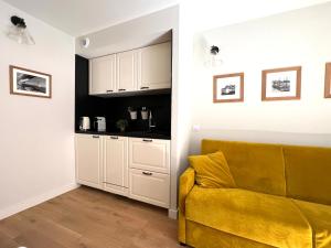 a living room with a yellow couch and a kitchen at Les Petits Volets 3 appartements au choix in Antibes