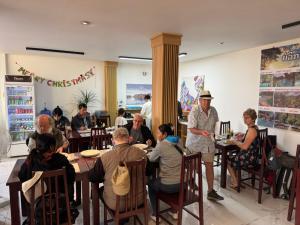 un grupo de personas sentadas en mesas en un restaurante en Vang Vieng Green Hotel, en Vang Vieng