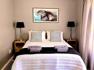 una camera da letto con un letto con due lampade e un quadro di un cavallo di The Kei Mouth Guest Lodge Collection a Kei Mouth