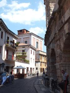 a man sitting on a bench in a street with buildings at La Terrazza sull'Arena in Verona