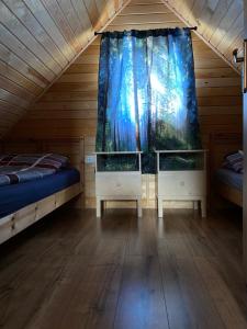 a room with two beds and a window at Gawra Nad Jeziorem - całoroczne domki nad jeziorem z balią, jacuzzi i sauną, Kaszuby in Sobącz