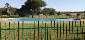 a swimming pool in a field behind a green fence at Ebenhaeser overnight accomodation in Bela-Bela