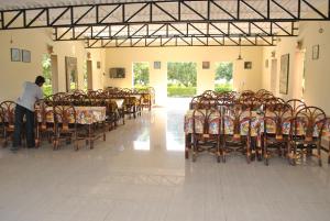 a man standing in a room with tables and chairs at Gir Jungle Lodge in Sasan Gir