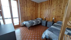 a bedroom with two beds in a room with wooden walls at LinHaus in Limone Piemonte