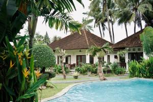 a villa with a swimming pool in front of a house at Abian Bali Resort Amed in Amed