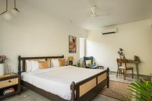 a bedroom with a large bed and a chair at Da Alohas Hibiscus Oasis Pool Facing Candolim in Betim +19 photos