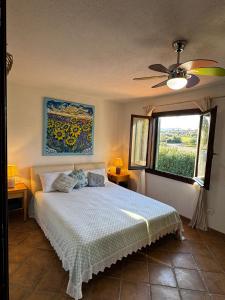 Un dormitorio con una cama con ventilador de techo y una ventana. en Sardegna Porto San Paolo, en Porto San Paolo