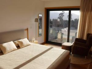 ein Schlafzimmer mit einem Bett und einem großen Fenster in der Unterkunft Casa do Norte in Póvoa de Lanhoso + 42 Fotos