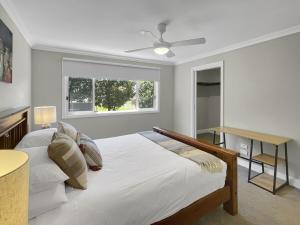 una camera da letto bianca con un letto e una finestra di The Nest by Batemans Bay a Batemans Bay