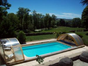 a swimming pool with an arch around it at Le Château de Vernières in Talizat