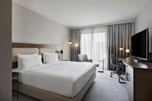 a hotel room with a bed and a flat screen tv at Courtyard by Marriott Munich City East in Munich