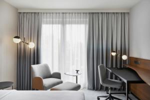 a hotel room with a desk and a bed and a desk and chairs at Courtyard by Marriott Munich City East in Munich