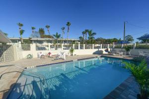 a swimming pool at a resort with people sitting around it at Regency Inn & Suites Sarasota in Sarasota