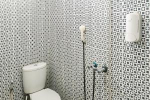 a bathroom with a toilet in a black and white tiled wall at RedDoorz at Amanah Syariah Residence Tanjung Karang Lampung in Tanjungkarang +19 photos