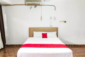 a bedroom with a white bed with a red pillow at RedDoorz at Amanah Syariah Residence Tanjung Karang Lampung in Tanjungkarang