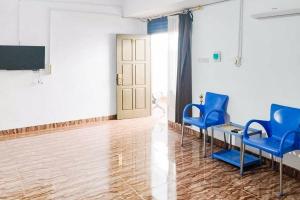 a waiting room with blue chairs and a tv at RedDoorz at Amanah Syariah Residence Tanjung Karang Lampung in Tanjungkarang