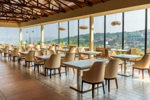 a restaurant with tables and chairs and windows at The White Rock Inn & Dine in Shillong