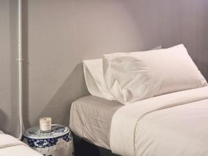 a bed with white pillows and a candle on a table at Human Touch Room - Soulful Bangkok Hideout in Lat Krabang