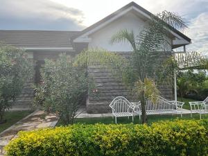 two white benches sitting in front of a house at Kameso Farm guest house in Muhoroni