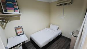 a small room with a white bed and a mirror at Natol Homestay - LA Tabuan Jaya in Kuching