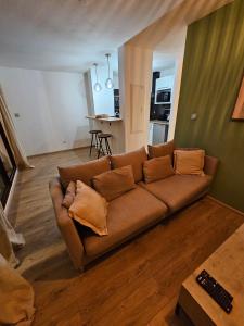 a living room with a brown couch and a kitchen at La Riviera in Saint-Denis