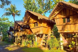 a large wooden house with a palm tree behind it at Surfer's Villa La Union in San Juan