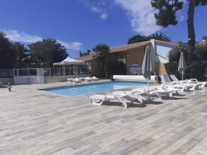 a group of lounge chairs and umbrellas next to a swimming pool at Oléron La Cotinière Camping Nature & Calme, Piscine, Plage à 150m in La Cotinière