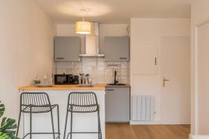 una cocina con 2 taburetes y una barra en Appartement une chambre avec parking et balcons, en Tourcoing
