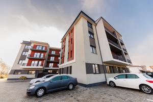 two cars parked in a parking lot in front of a building at Apartament de lux cu jacuzzi in Timisoara in Timişoara