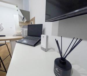a laptop computer on a counter with a vase with sticks at Anna Home in Telde