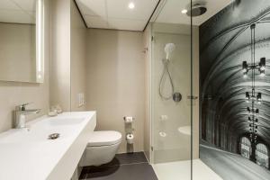 a bathroom with a shower and a toilet and a sink at NH Amsterdam Schiphol Airport in Hoofddorp