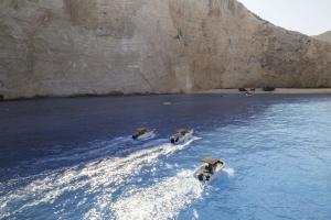 three boats in the water near a large cliff at The Sall Suites Complex A - Iconic Sea Views, by ZanteWize in Agios Nikolaos